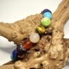 Bracelet en 8 mm avec 3 fois les 7 pierres représentant les 7 chakras posé sur morceau de bois