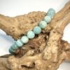 Bracelet en amazonite posé sur morceau de bois et fond blanc