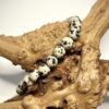 Bracelet en 6 mm en Jaspe dalmatien posé sur morceau de bois