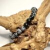 Bracelet en 6 mm en obsidienne neige posé sur morceau de bois