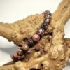 Bracelet en 6 mm en rhodonite black line posé sur morceau de bois