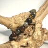Bracelet homme en pierre d'oeil de tigre, d'oeil de faucon et d'oeil de taureau avec ornement en metal posé sur morceau de bois