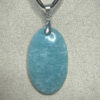 Pendentif format ovale en amazonite avec son attache en acier suspendu sur présentoir beige par cordon noir