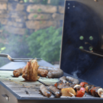 barbecue en fonctionnement avec viande et fourchette qui retourne un morceau de poulet