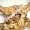 Bracelet en quartz rose 6 mm posé sur morceau de bois