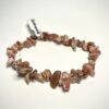 Bracelet bohème en pépite de pierre de rhodochrosite posé sur fond blanc