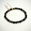 Bracelet en 6 mm. trio de protection de pierres d'oeil de tigre, d'obsidienne et d'hématite posé sur morceau de bois