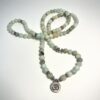 Mala en Amazonite vert avec ornement en métal représentant un Om replié en T sur fond blanc