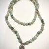 Mala en Amazonite vert et ornement en métal représentant un Om, replié en deux, sur fond blanc