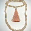 Mala en Aventurine rose et ponpon d'ornement rose replié en deux sur fond blanc