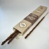 Boite de bâton d'encens de palo santo et vanille ouverte avec les bâtons dépassant légèrement du paquet, et un bâton sur le côté bien visible. Bâton d'encens avec des copeaux lié à la tige d'encens de palo Santo