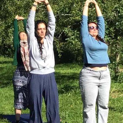3 femmes s'étirant les bras en l'air en pleine nature